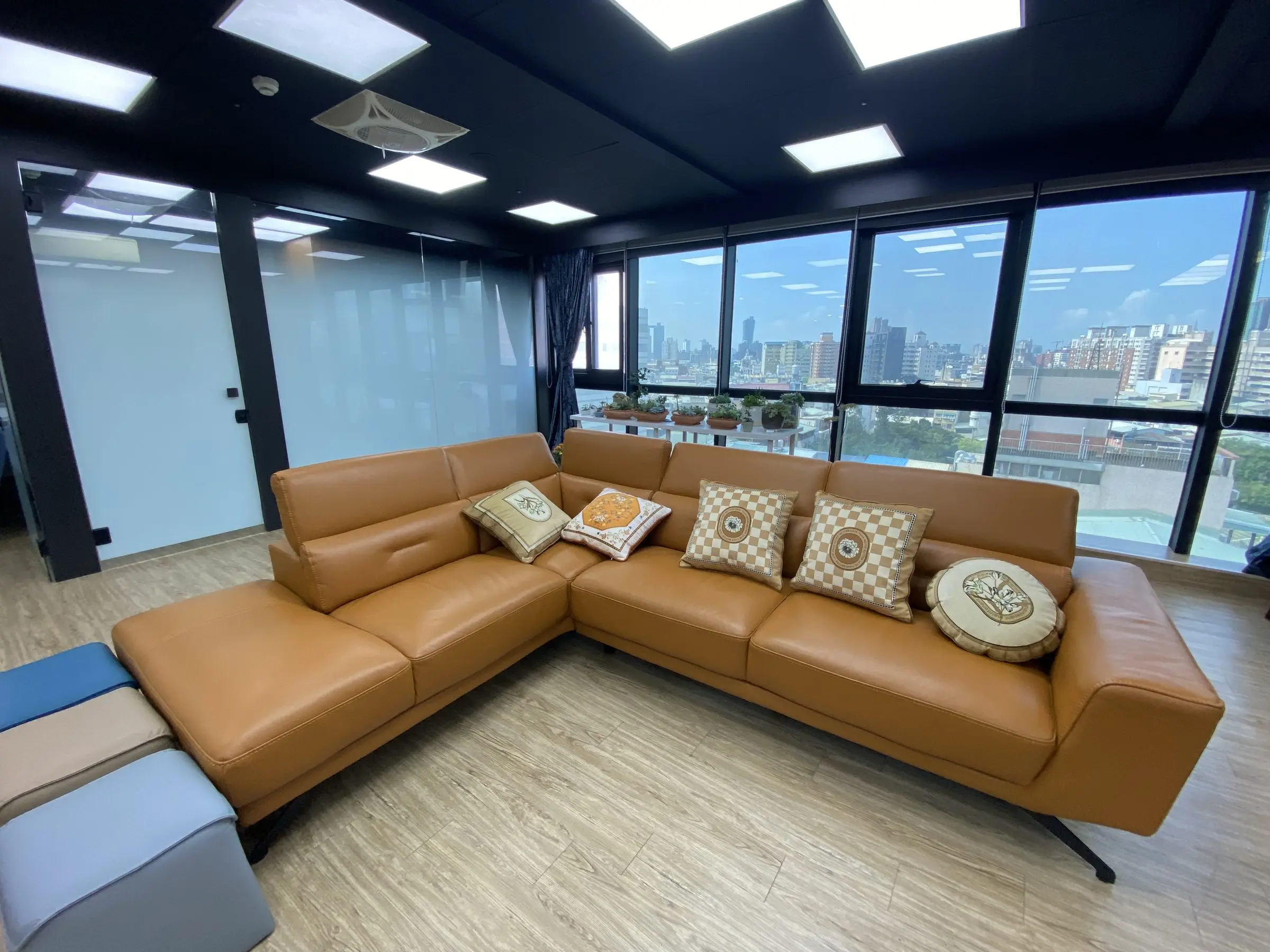Podcast Space 現場實拍：落地窗前的 L 型皮沙發，窗外是台中市景
