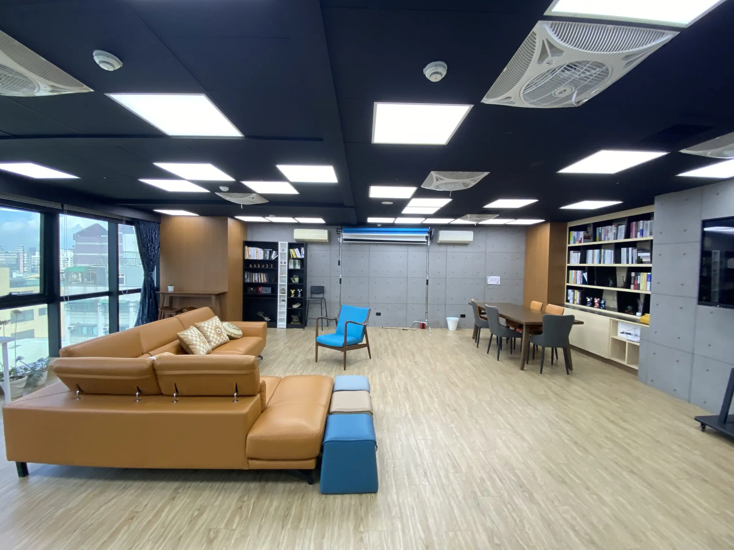 Podcast Space 現場實拍全景：沙發區、書牆、木桌與背景紙架