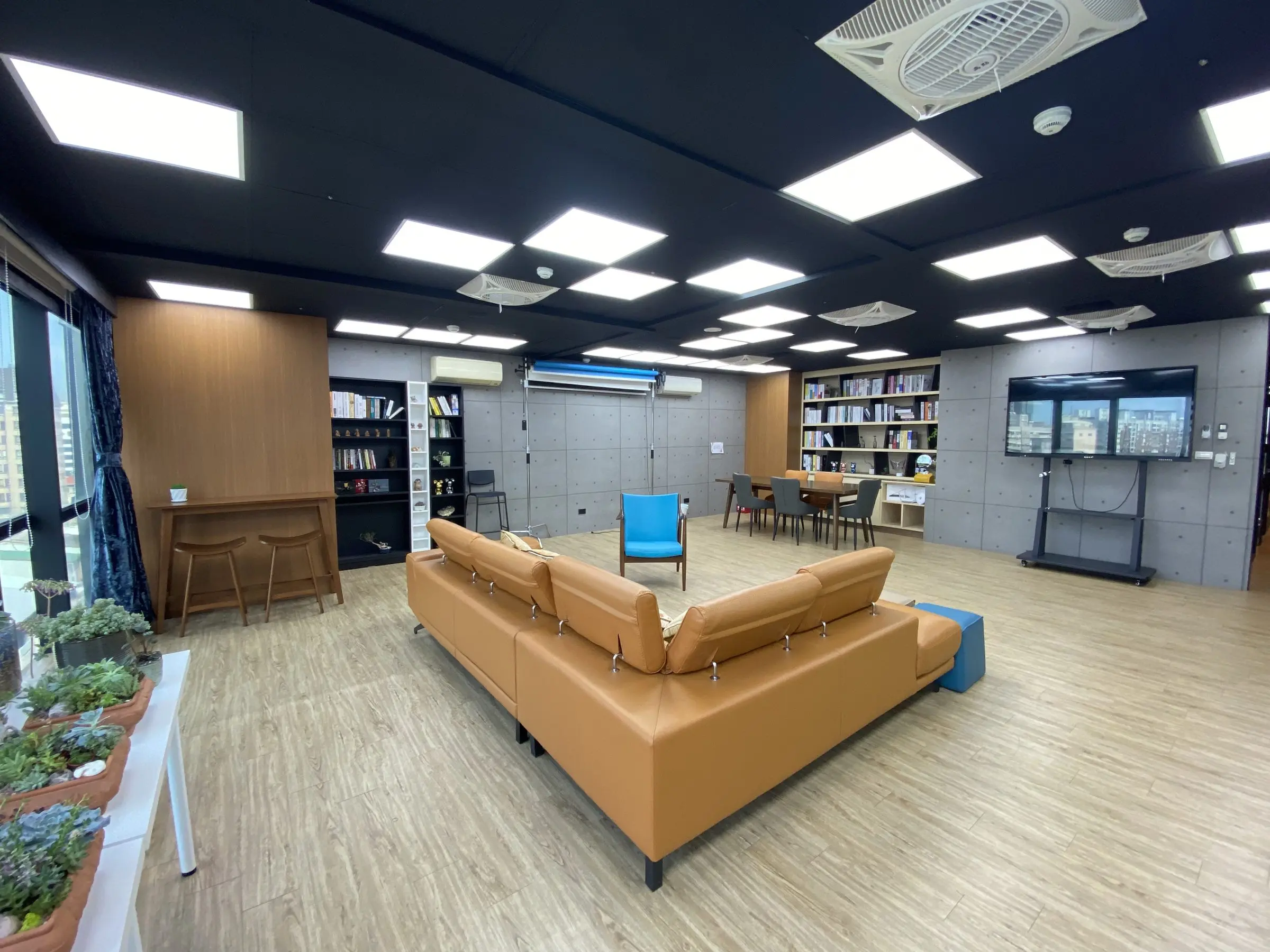 Podcast Space 現場實拍：皮沙發區、書牆、電視與拍攝用背景紙架